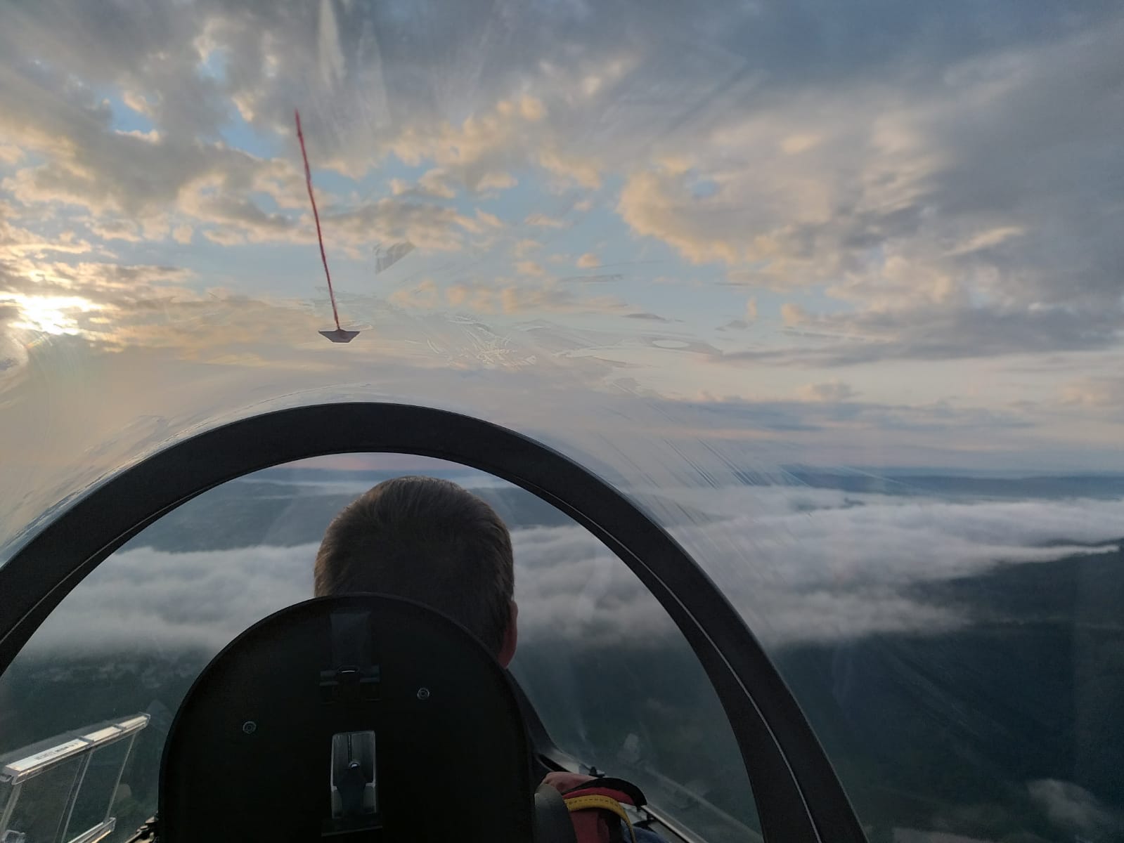 Blick vom hinteren Sitz einer ASK 21 bei einem Flug bei Sonnenaufgangsstimmung über Bodennebel im Rheintal.