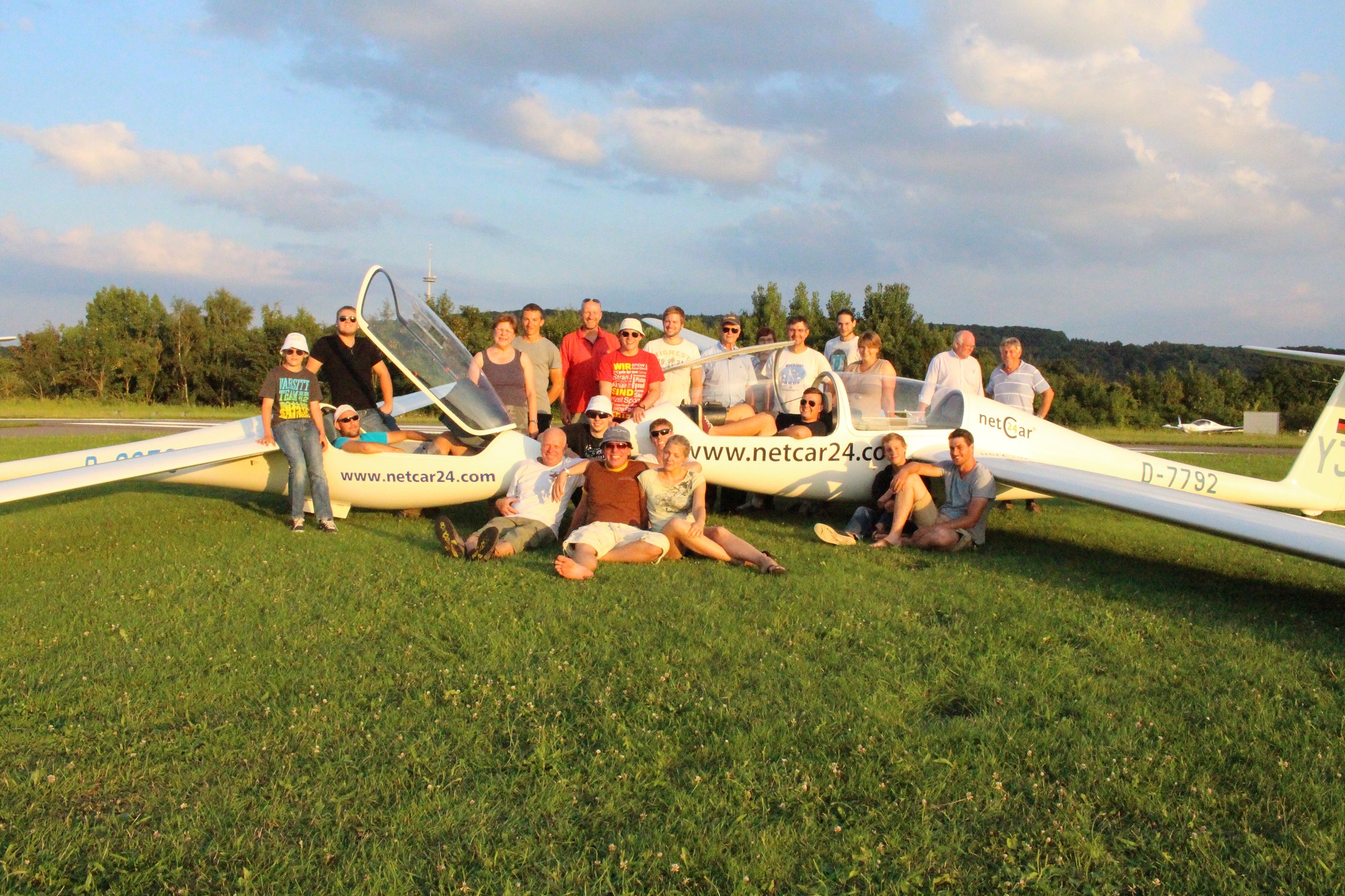 Gruppenfoto mit vielen Menschen - jung und alt - rund um zwei Segelflugzeuge, die sich gegenüberstehen.