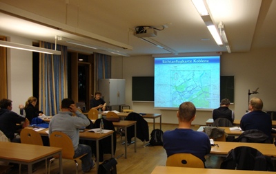 Seminarraum in dem ein Lehrer anhand einer Beamerfolie die Anflugkarte von Koblenz erklärt. Schüler sitzen in den Reihen und hören zu.