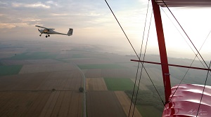 Blick aus einem roten Doppeldecker auf die Eifellandschaft und das parallel fliegende UL des Aero-Club Koblenz.